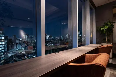 a long wooden table in a room with a view of a city at Tokyu Stay Aoyama Premier in Tokyo