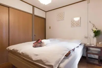 a bedroom with a large white bed and a desk at Ogi-Ohashi Apartment in Tokyo