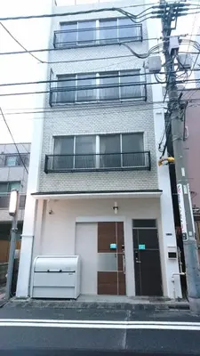 a white building with a balcony on a street at Rimon Apartment in Tokyo