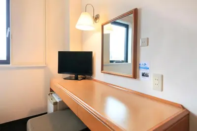 a room with a desk with a television and a mirror at Smile Hotel Tokyo Ayase Ekimae in Tokyo