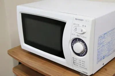 a white microwave oven sitting on a wooden shelf at Smile Hotel Tokyo Ayase Ekimae in Tokyo