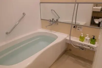 a bath tub in a bathroom with two bottles at Hotel Ryumeikan Tokyo in Tokyo