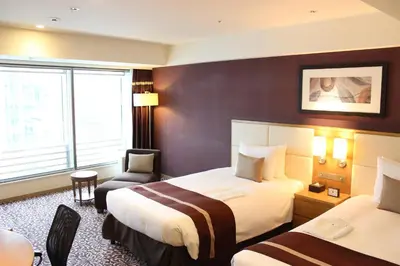 a hotel room with two beds and a chair at Hotel Ryumeikan Tokyo in Tokyo