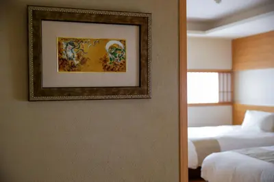 a room with two beds and a picture on the wall at Kaminarimon Ryokan in Tokyo
