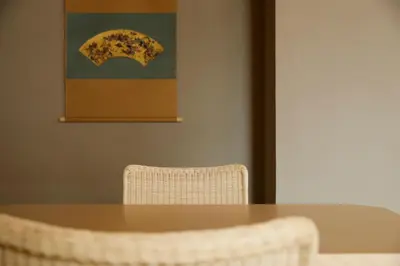 a table and a chair with a painting on the wall at Kaminarimon Ryokan in Tokyo