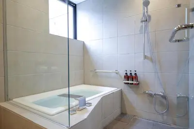 a bathroom with a tub and a glass shower at Kaminarimon Ryokan in Tokyo