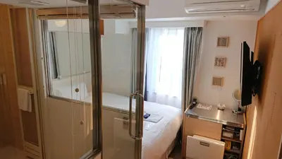 a bedroom with a glass shower and a bed at EN Hotel Shibuya in Tokyo