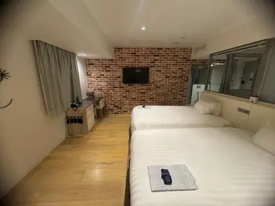 two beds in a room with a brick wall at EN Hotel Shibuya in Tokyo