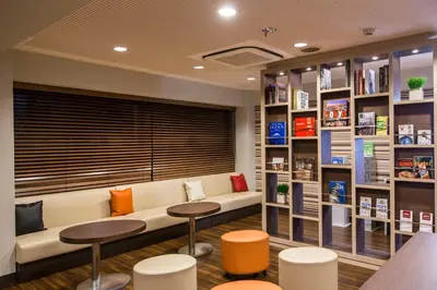 a library with a couch and two tables and shelves at HOTEL MYSTAYS Asakusa in Tokyo