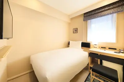 a bedroom with a white bed and a desk and a window at Hotel Nihonbashi Saibo in Tokyo