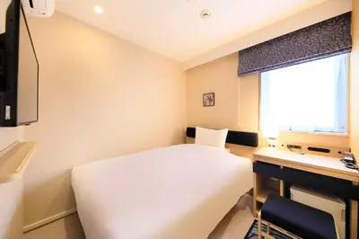 a bedroom with a white bed and a desk and a window at Hotel Nihonbashi Saibo in Tokyo