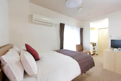a bedroom with a white bed with pillows and a television at HOTEL MYSTAYS Ueno Iriyaguchi in Tokyo