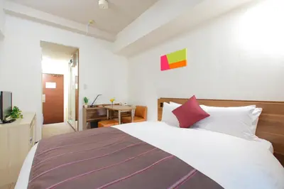 a bedroom with a large white bed with red pillows at HOTEL MYSTAYS Ueno Iriyaguchi in Tokyo