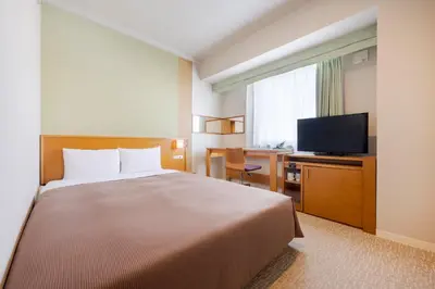 a hotel room with a bed and a flat screen tv at Candeo Hotels Ueno Park in Tokyo