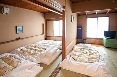 a room with three beds in it with a tv at Hotel Edoya in Tokyo