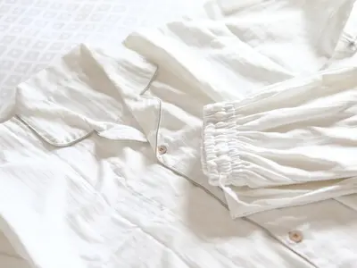 a white shirt laying on top of a bed at KOKO HOTEL Ueno Station - formerly Hotel Wing International Select Ueno Okachimachi in Tokyo
