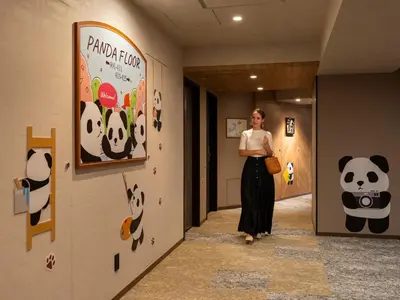 a woman is standing in a hallway with a panda sign at Mitsui Garden Hotel Ueno in Tokyo
