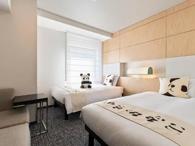 a hotel room with two beds with a panda bear on the bed at Mitsui Garden Hotel Ueno in Tokyo