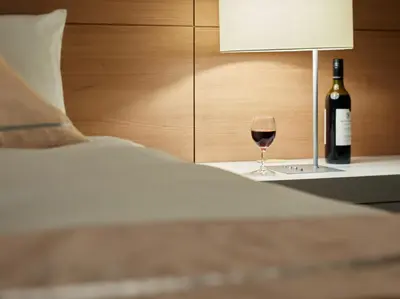 a glass of wine sitting on a table next to a bed at Mitsui Garden Hotel Ueno in Tokyo