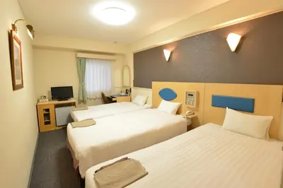 a hotel room with two beds and a television at Hotel Marutani in Tokyo