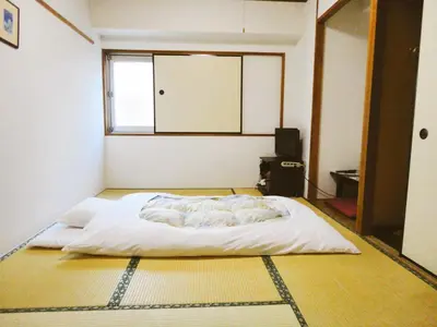 a bedroom with a white bed with a window at Hotel Marutani in Tokyo