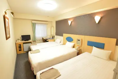 a hotel room with two beds and a television at Hotel Marutani in Tokyo