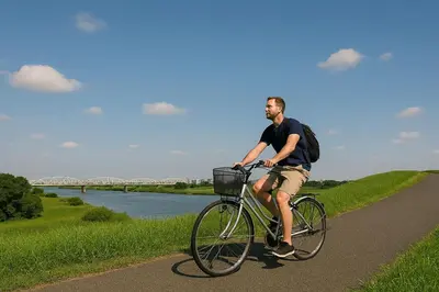 a man riding a bike on a path next to a river at Sky Heart Hotel Koiwa in Tokyo