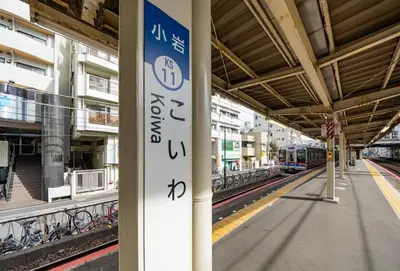 a train station with a train on the tracks at Sky Heart Hotel Koiwa in Tokyo