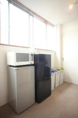 a kitchen with a microwave on top of a refrigerator at Base Inn Tabata in Tokyo