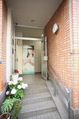 a staircase leading to a building with a poster on the wall at Base Inn Tabata in Tokyo