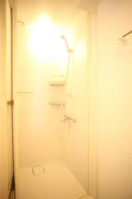 a white bathroom with a shower and a toilet at Base Inn Tabata in Tokyo