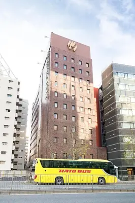a yellow bus parked in front of a tall building at Ginza Capital Hotel Akane in Tokyo