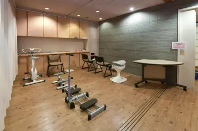 a gym with chairs and a table and a table and dumbbells at Refre Forum in Tokyo