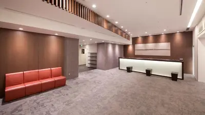 a lobby with a red couch and a reception desk at Hotel Grand City in Tokyo