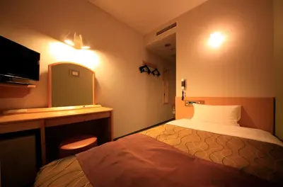 a hotel room with a bed and a desk and a television at Hotel Grand City in Tokyo
