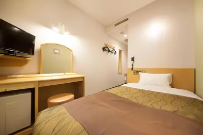 a small hotel room with a bed and a tv at Hotel Grand City in Tokyo