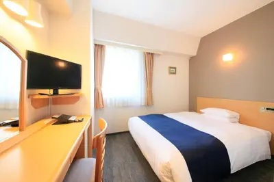 a hotel room with a bed and a desk with a television at Hotel Grand City in Tokyo