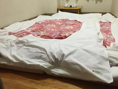 a bed is covered with a white sheet at Asakusa Hotel Fukudaya in Tokyo