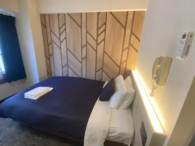 a room with a bed with a phone on the wall at HOTEL LiVEMAX BUDGET Higashi Ueno in Tokyo