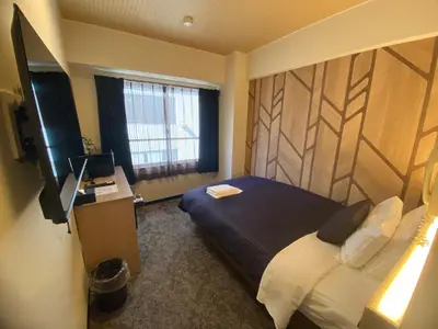 a bedroom with a bed and a desk with a computer at HOTEL LiVEMAX BUDGET Higashi Ueno in Tokyo