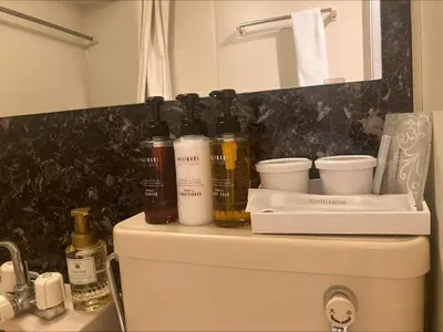 a pile of bottles on top of a toilet in a bathroom at HOTEL LiVEMAX BUDGET Higashi Ueno in Tokyo