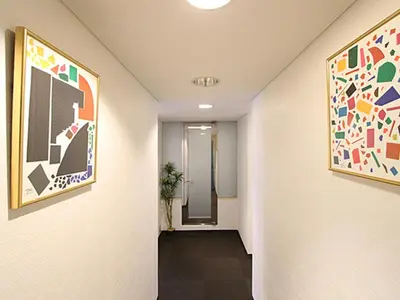 a hallway with paintings on the walls and a hallway with a hallway at HOTEL LiVEMAX BUDGET Korakuen in Tokyo