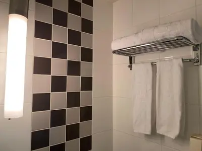 a bathroom with black and white tiled walls and white towels at Hotel Trusty Tokyo Bayside in Tokyo