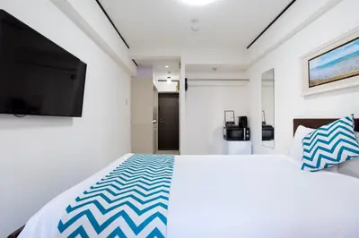a bedroom with a large bed and a flat screen tv at G-stays Shinjuku in Tokyo