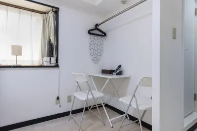 a room with white walls and a table and chairs at G-stays Shinjuku in Tokyo
