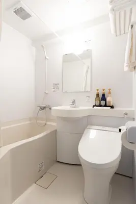 a white bathroom with a toilet and a sink and a tub at G-stays Shinjuku in Tokyo