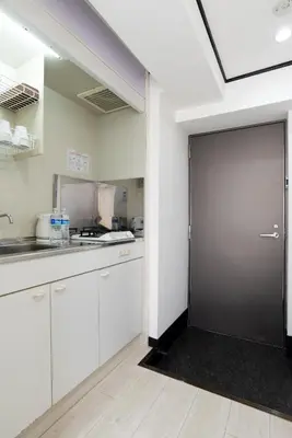 a kitchen with white cabinets and a large door at G-stays Shinjuku in Tokyo