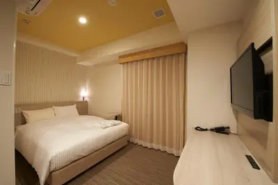 a bedroom with a bed and a flat screen tv at Sotetsu Fresa Inn Ginza Sanchome in Tokyo