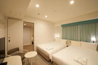 a hotel room with two beds and a mirror at Sotetsu Fresa Inn Ginza Sanchome in Tokyo