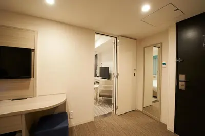 a room with a desk and a room with a television at Sotetsu Fresa Inn Ginza Sanchome in Tokyo